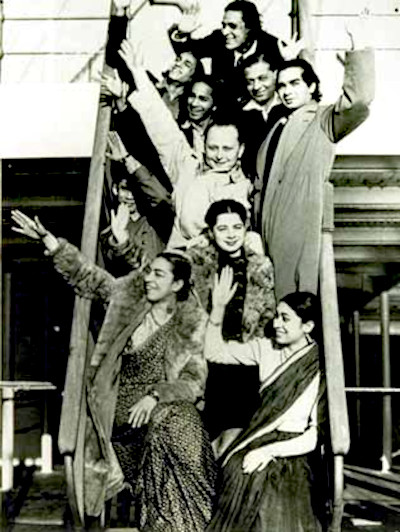 Uday Shankar brought his dance troupe to Almora to serve as teachers at the culture centre, seen here just before their departure for New York in 1937. In the forefront, at the bottom of the stairs are sisters Zohra and Uzra. Standing between them is French dancer, Simkie. Directly behind Simkie stands Vishnu Dass Shirali who played the tabla taranga and mridanga. To his left and partially hidden is Uday Shankar's cousin, Kanak-Lata, a dancer. To his right is Uday Shankar. Towards the back are Uday's brothers, Debendra, Rajendra and Robindra; and sarod player, Timir Baran Bhattacharya.
